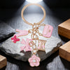 Pendentif de cœur doré et rose avec nœud floral sur anneau circulaire, exposé sur une pierre grise.