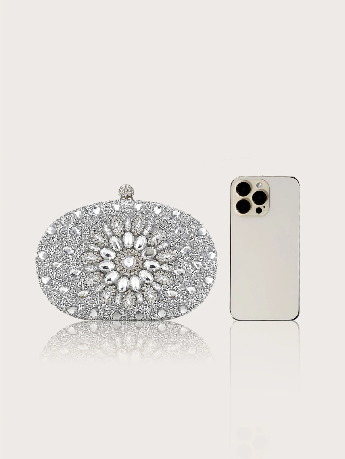 Pochette à clochette de strass et boîte, exposée à côté d'un smartphone blanc.