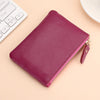 A deep magenta genuine leather mini zipper coin and card purse resting on a light beige surface next to a white keyboard.