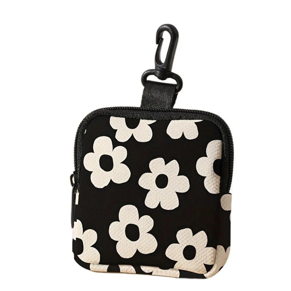 Black coin purse with a white floral pattern and a black hook closure.