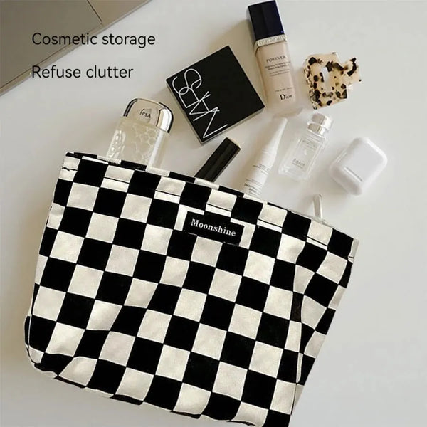 A black and white checkered plaid cosmetic storage bag is shown with various beauty products on a white surface.