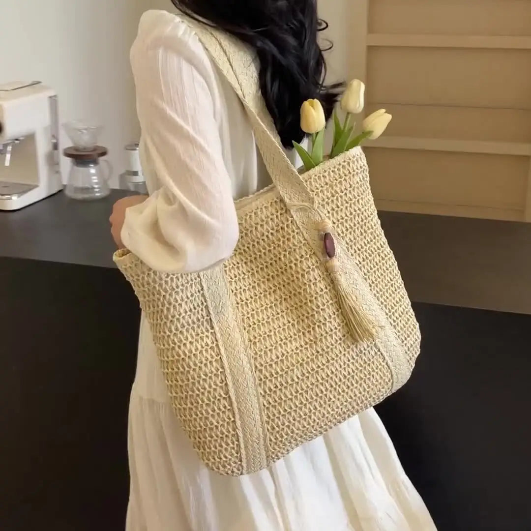 A woman holds a natural straw woven tote bag with yellow tulips against a light background.