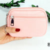 A hand holds a pink PU leather mini wallet with a silver keychain on a white background.