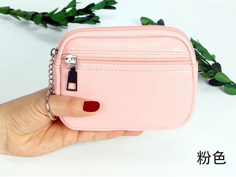 A hand holds a pink PU leather mini wallet with a silver keychain on a white background.