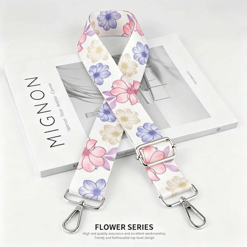A white and pink floral patterned nylon shoulder strap for bags and purses displayed on a white box.