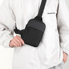 Una persona con una chaqueta blanca sostiene un bolso cruzado negro impermeable.