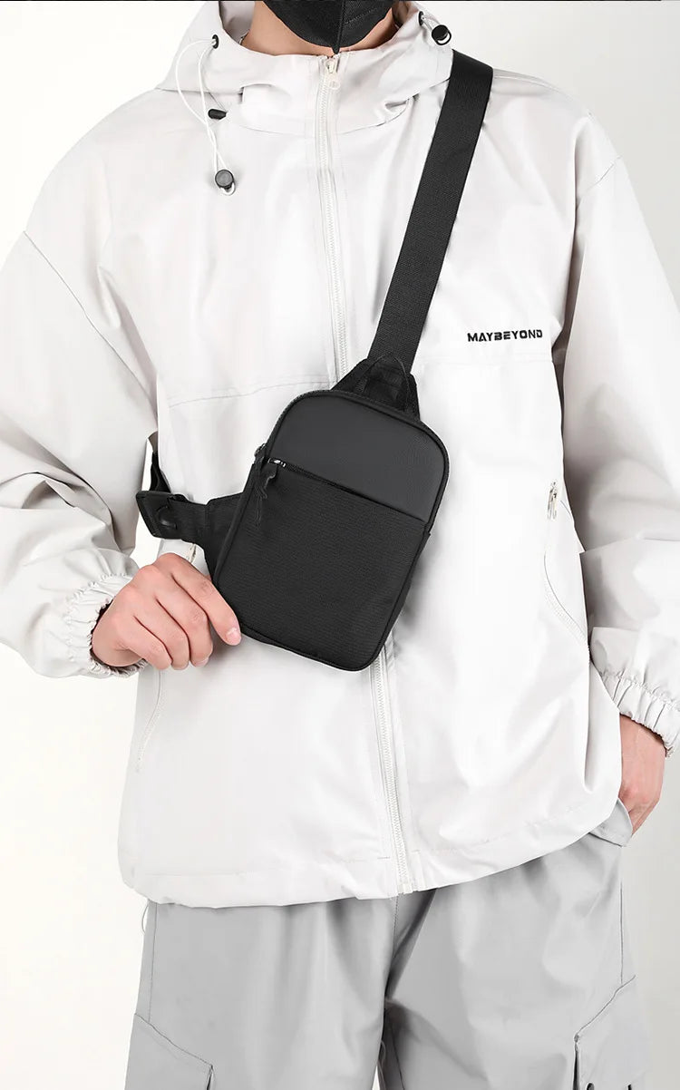 Una persona con una chaqueta blanca sostiene un bolso cruzado negro impermeable.