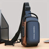 A dark blue men's oxford sling chest bag with a brown leather accent and black strap resting on a wooden surface.