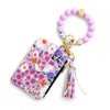 A purple and white floral patterned silicone bead PU leather key chain wallet with a gold charm and tassel.
