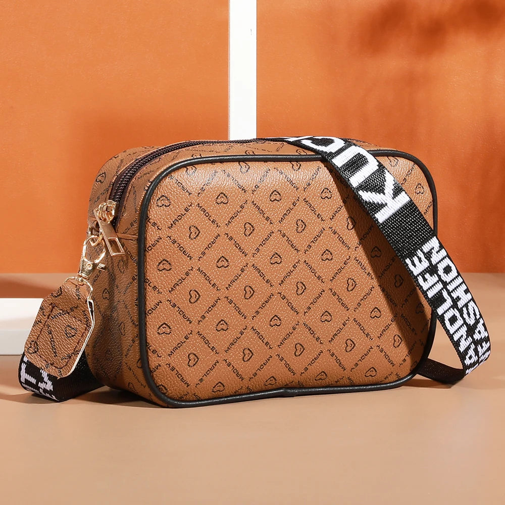 A brown patterned fashion crossbody shoulder bag with black trim and a black strap.