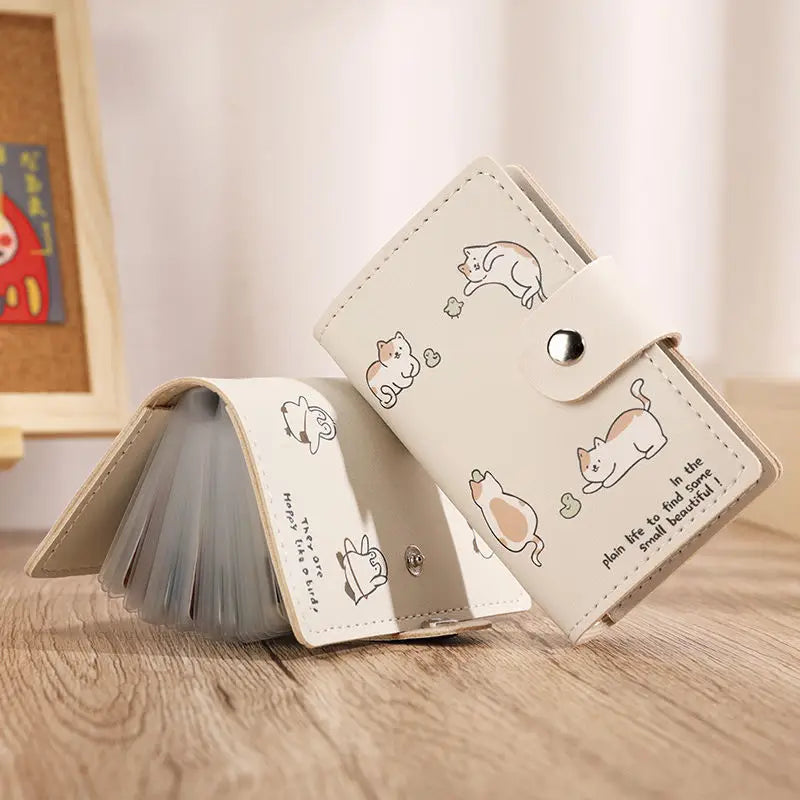 Helles beiges Cartoon-Katzen-ID-Karten-Wallet mit Falldesign auf einer Holzoberfläche.