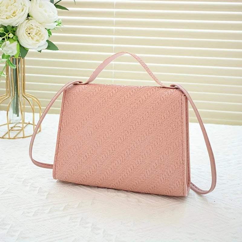 A light pink beaded square crossbody bag with a pink adjustable strap resting on a white surface.