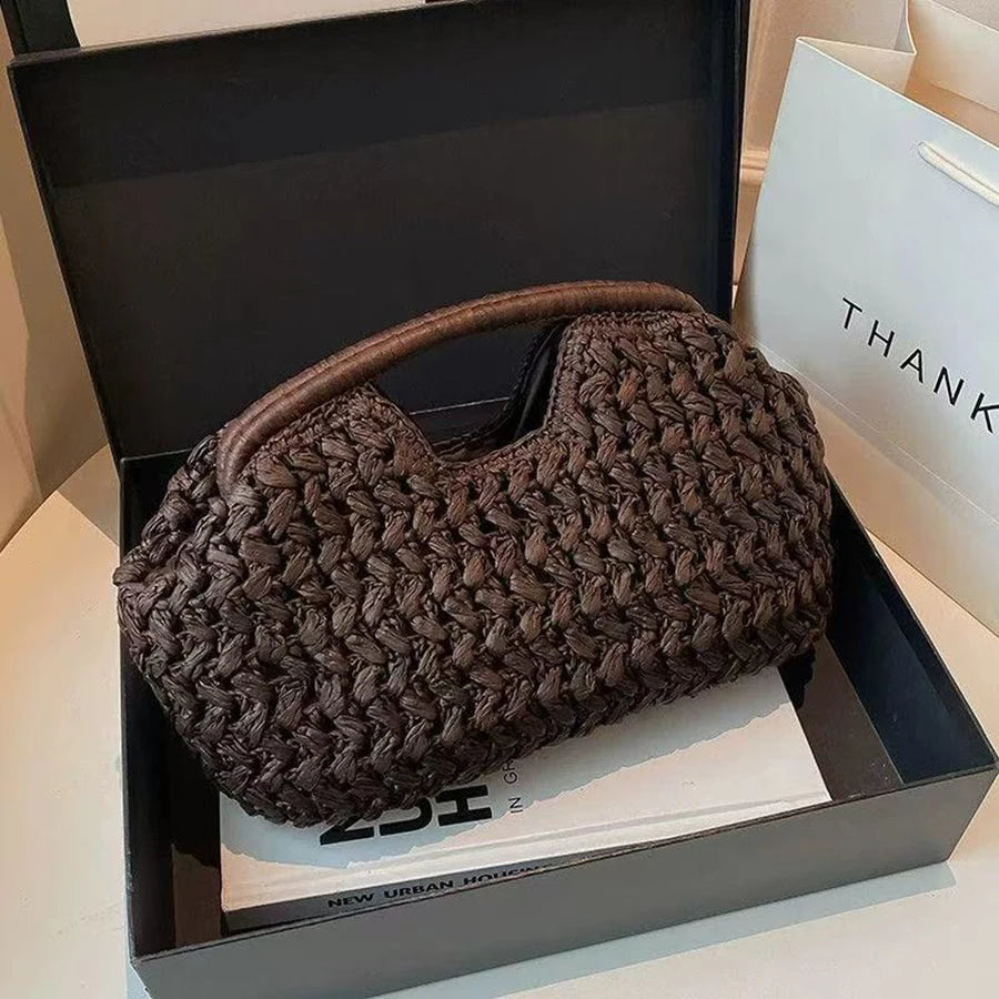 Un pochette à clochette en fibre naturelle brun foncé est présentée dans une boîte noire avec une carte blanche.