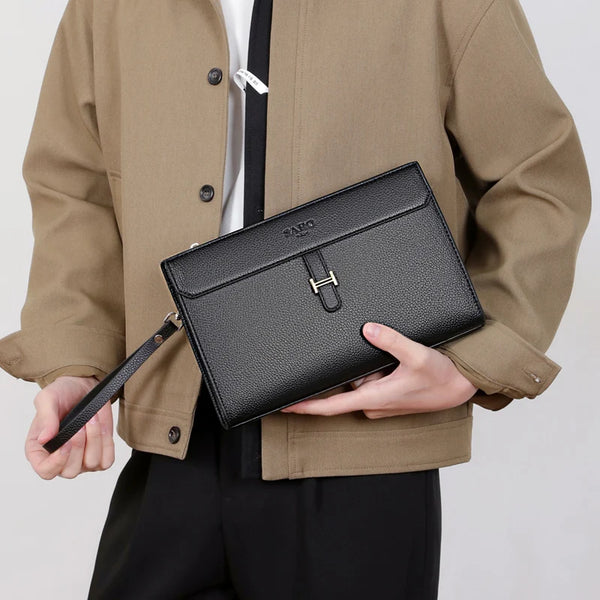 A man wearing a tan jacket holds a black PU leather clutch bag.