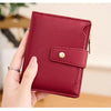 A hand holds a deep red textured card holder wallet with a leather flap and gold accent.