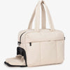 A beige large capacity women's travel duffle bag with padded handles and a zippered closure.