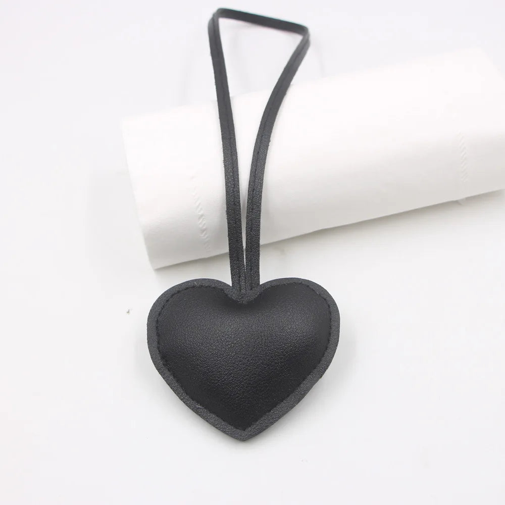 A black PU leather heart-shaped keychain hanging from a loop against a white background.