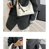 A woman holds a white retro PU leather shoulder bag with gold hardware against a dark gray suit jacket.