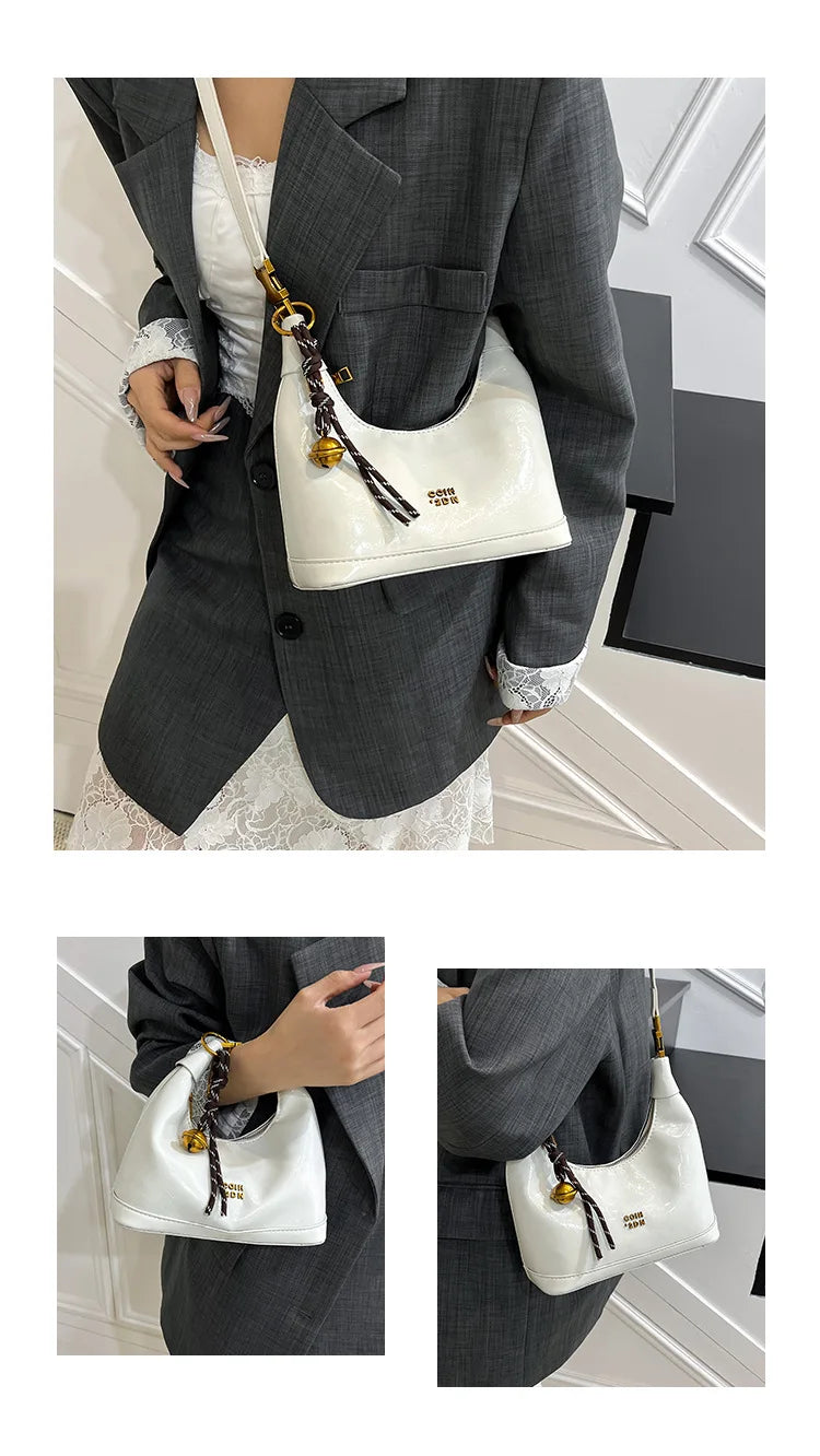 A woman holds a white retro PU leather shoulder bag with gold hardware against a dark gray suit jacket.