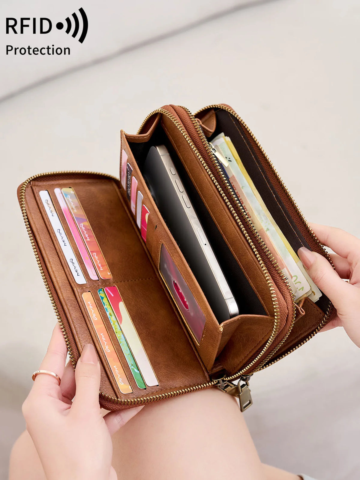 A brown vintage double-zipper wallet is shown open, displaying various cards and a smartphone.