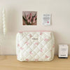 Sac de rangement cosmétique rose en patchwork avec motif nœud sur une surface en bois.