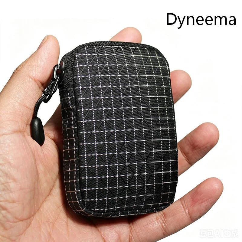 Une pochette utilitaire noire Dyneema à motif à carreaux est tenue dans une main.