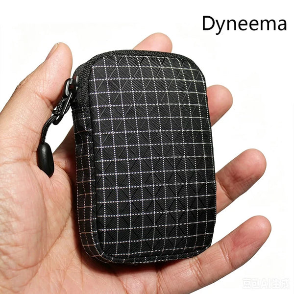 Eine schwarze Dyneema-Nützlichkeitstasche mit Karomuster wird in einer Hand gehalten.