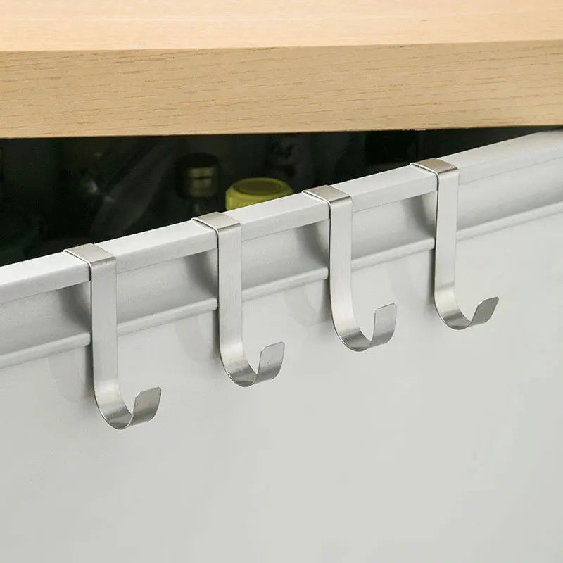Silver heavy duty hook rack for cabinet doors mounted on a white cabinet frame.