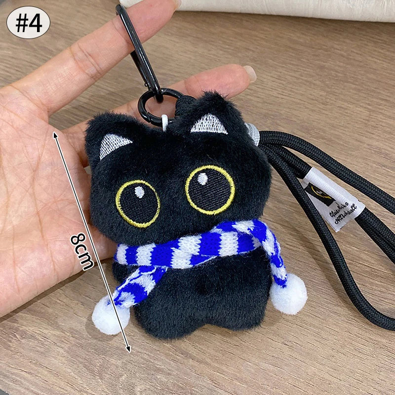 Colgante de peluche de gato negro con cinta a rayas blancas y azules alrededor del cuello.