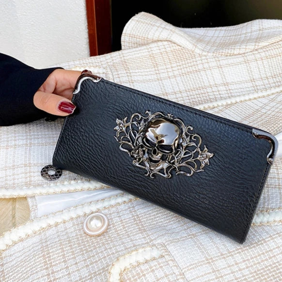 A black punk style long leather wallet resting on a cream textured fabric.