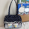 A black tote bag featuring white polka dots with a piano lace trim and bow detail.