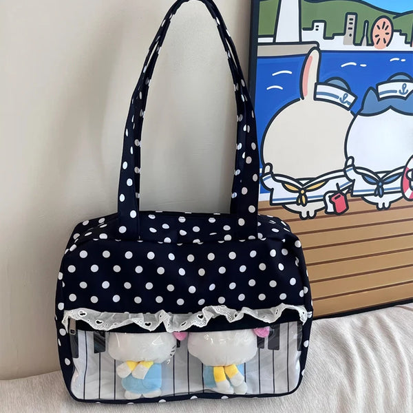 A black tote bag featuring white polka dots with a piano lace trim and bow detail.