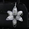 Silver realistic orchid flower keychain attached to a black leather handbag.