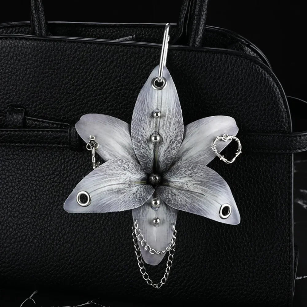 Silver realistic orchid flower keychain attached to a black leather handbag.