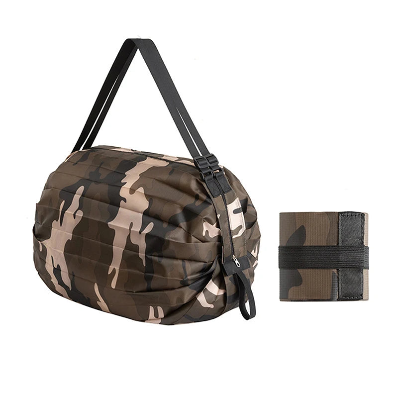 A camouflage patterned foldable nylon storage bag with a black handle and a matching fabric strap.