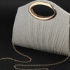 A silver glittery pleated circular evening handbag with a gold-toned chain draped below it.