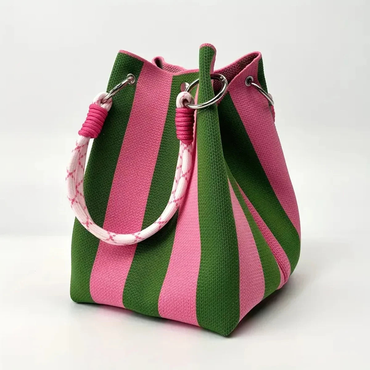 A pink and green striped retro knitted bucket handbag with pink cord handles.
