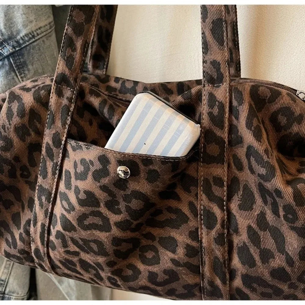 A close-up of a brown leopard print canvas tote bag showing a pocket with a striped cosmetic item.