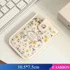 A beige floral patterned card wallet with a leather strap resting on a white surface.