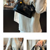 A black retro PU leather shoulder bag with gold hardware is shown against a light-colored shirt.