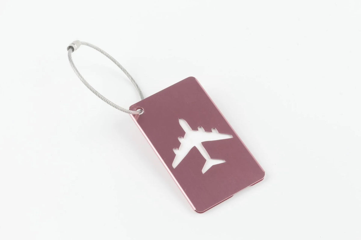 A maroon aluminum luggage tag with a silver cord attached, featuring a white airplane silhouette.