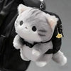 A grey soft cat plush pendant attached to a black backpack with a small charm.