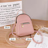 A pink waterproof PU mini backpack resting on a straw hat and next to a piece of paper.