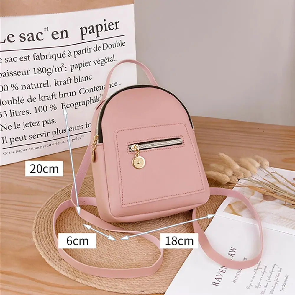 A pink waterproof PU mini backpack resting on a straw hat and next to a piece of paper.