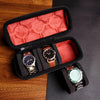 A black multi-slot travel watch organizer case with a red velvet lining, holding three watches.