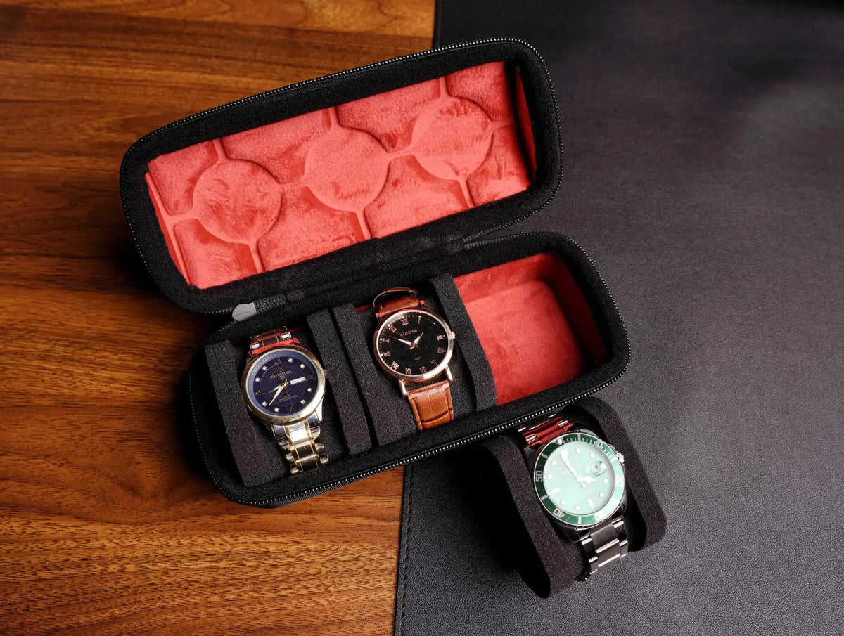 A black multi-slot travel watch organizer case with a red velvet lining, holding three watches.