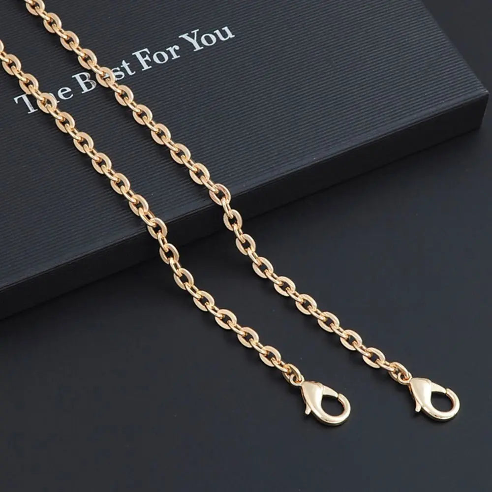 Gold metal chain strap for an adjustable crossbody bag, displayed on a dark surface.