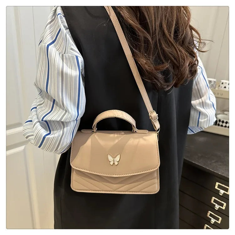 A beige textured shoulder messenger bag with a strap is shown against a dark background.