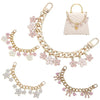 Accesorio de cadena de oro con corazones de esmalte y flores de cerezo, mostrado junto a un bolso acolchado.