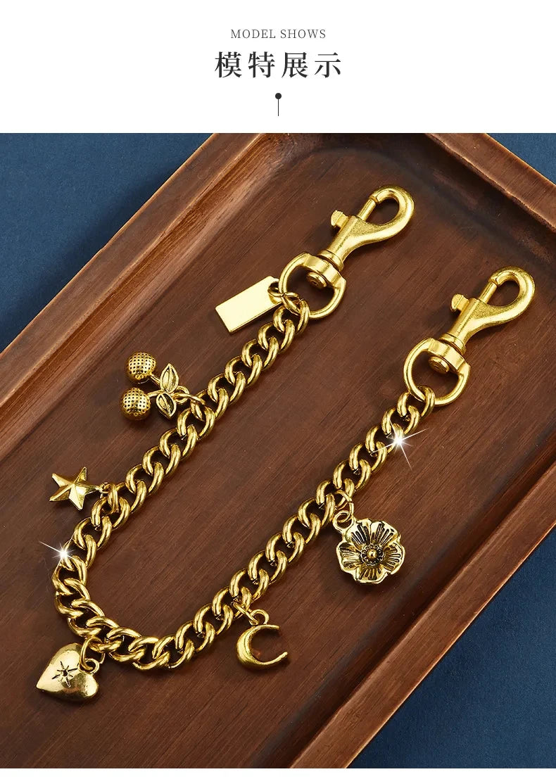 A gold-colored chain necklace with a charm featuring a cherry flower and a star, displayed in a wooden tray.